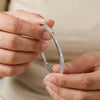 Close-up of hands holding a silver bracelet with intricate design