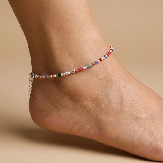Multicolored beaded anklet on a person's ankle against a beige background