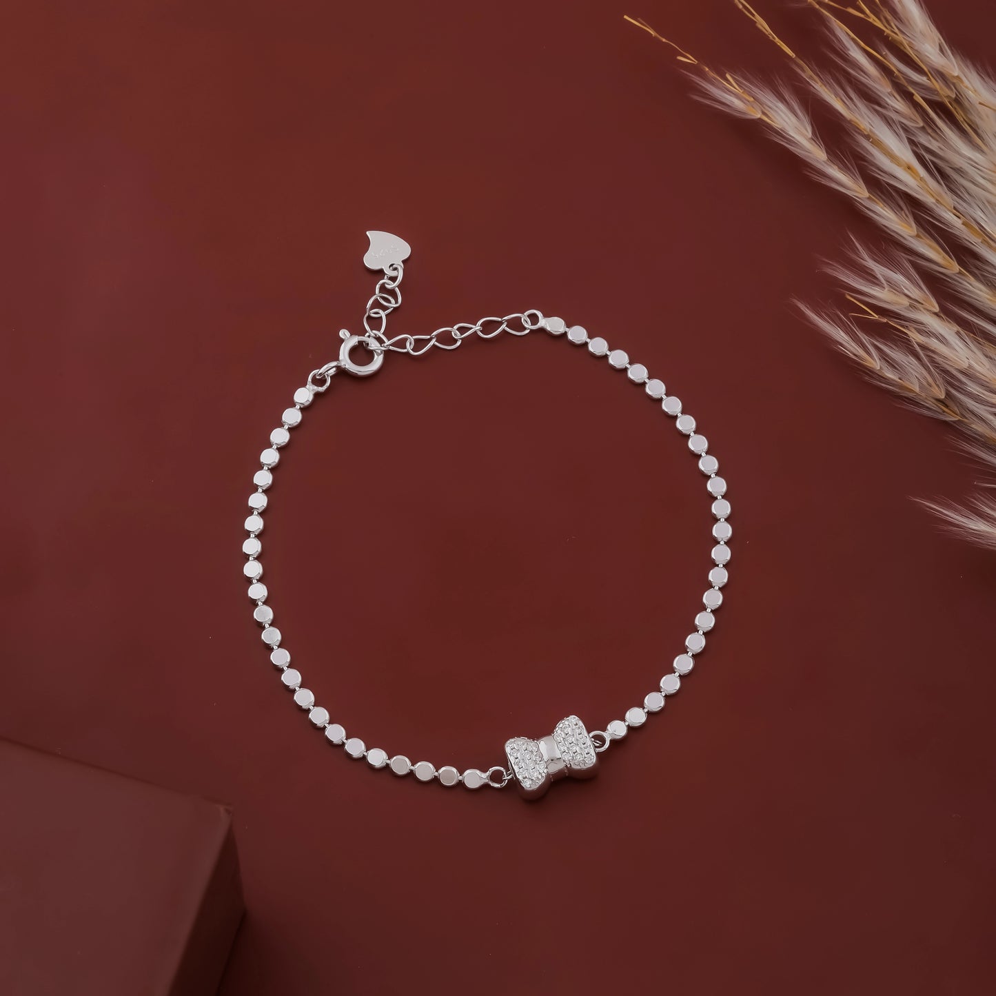Silver bracelet with a bow charm on a brown background