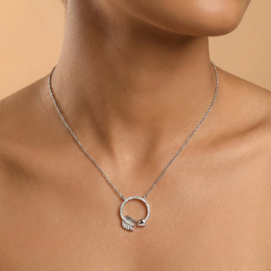 Silver necklace with a circular pendant on a person against a beige background