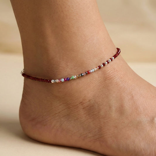 Multicolored beaded anklet on a person's ankle against a neutral background