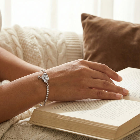 Hand with a bracelet on an open book, resting on a soft surface with pillows.