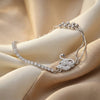 Silver bracelet with a pear-shaped diamond on a beige fabric background