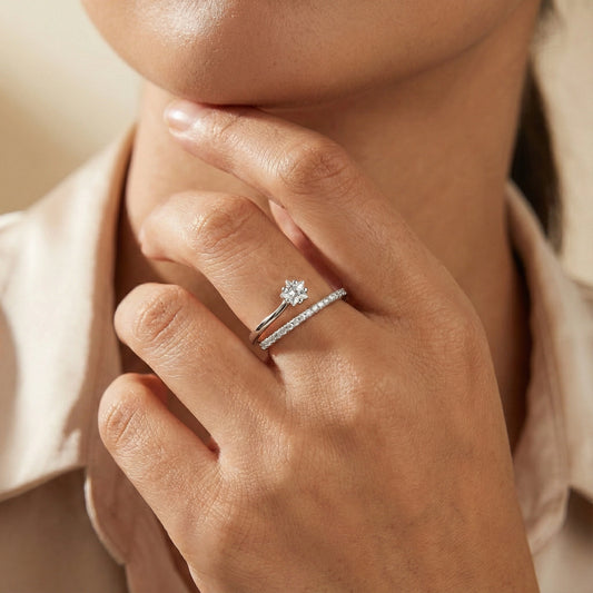 Close-up of a hand wearing two diamond rings with a soft background