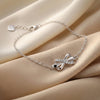Silver bracelet with a bow design on a beige fabric background