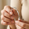 Close-up of hands holding a silver bracelet against a blurred background