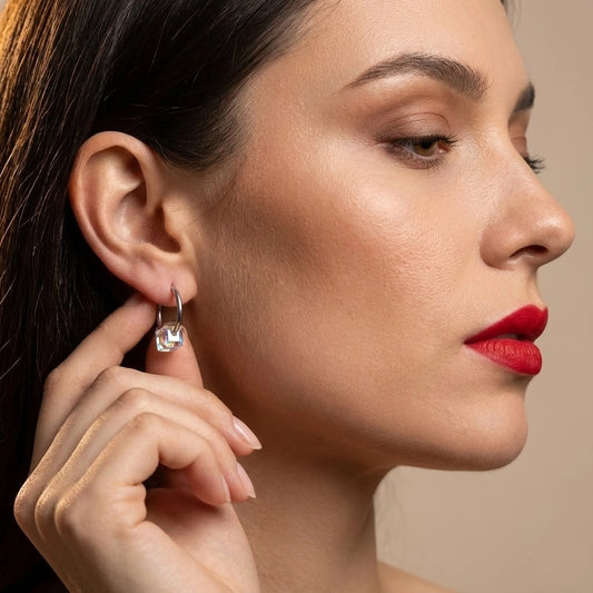 Close-up of a woman wearing a diamond earring on a beige background