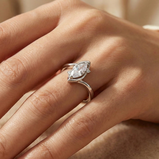 Close-up of a hand wearing a silver ring with a marquise-shaped diamond.