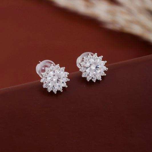 Silver earrings with clear stones on a brown surface