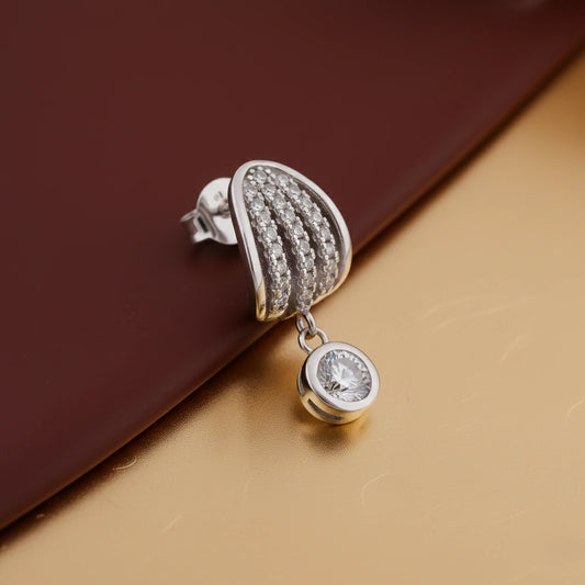Silver earring with a small diamond on a gold and brown background