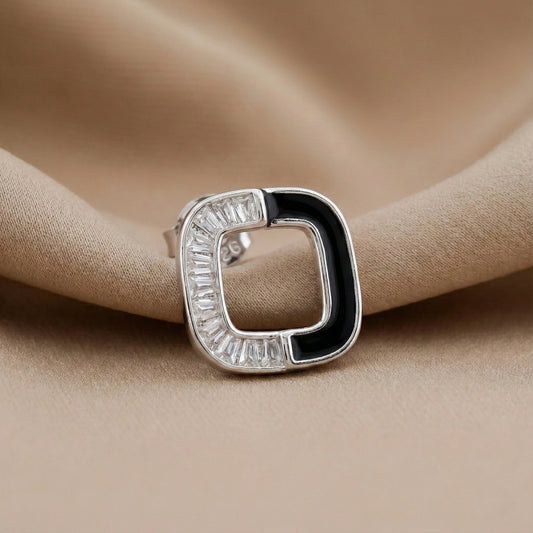 Silver ring with black and clear gemstones on beige fabric