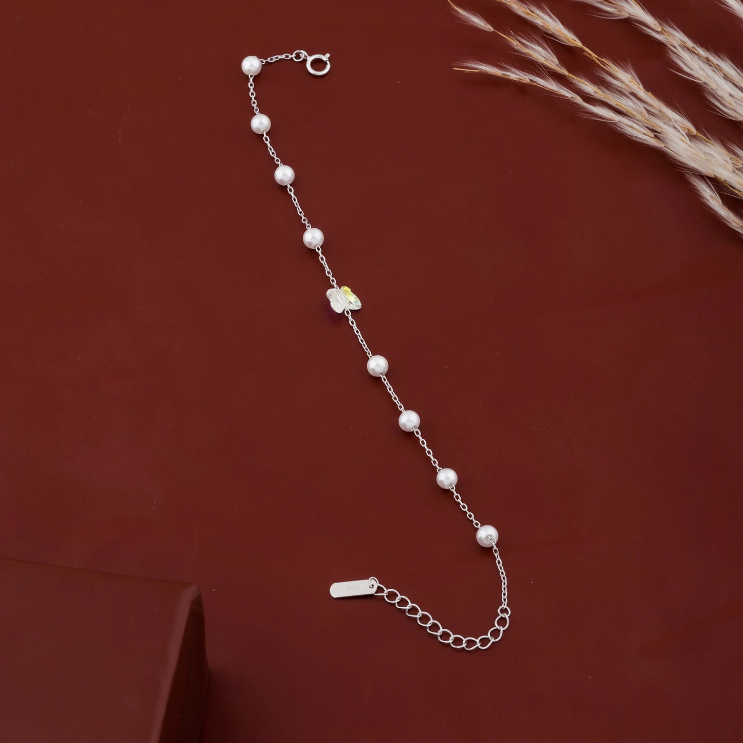 925 sterling silver bracelet with white pearls and butterfly charm on maroon background