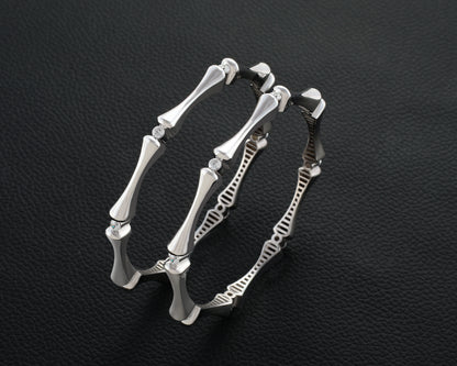 Silver bracelet with bone-like design on a dark textured background