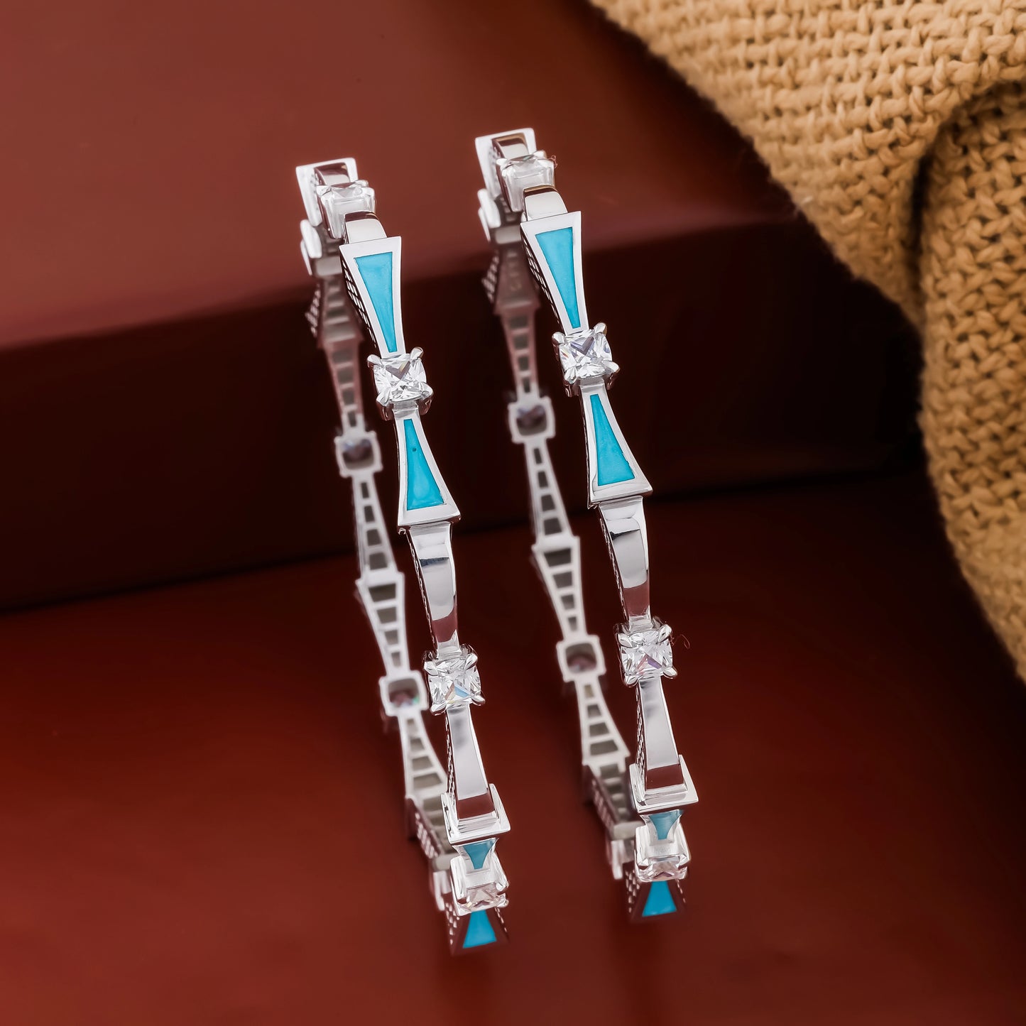 Pair of silver earrings with blue accents on a brown background