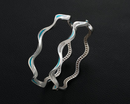 Silver hoop earrings with blue accents on a dark textured background