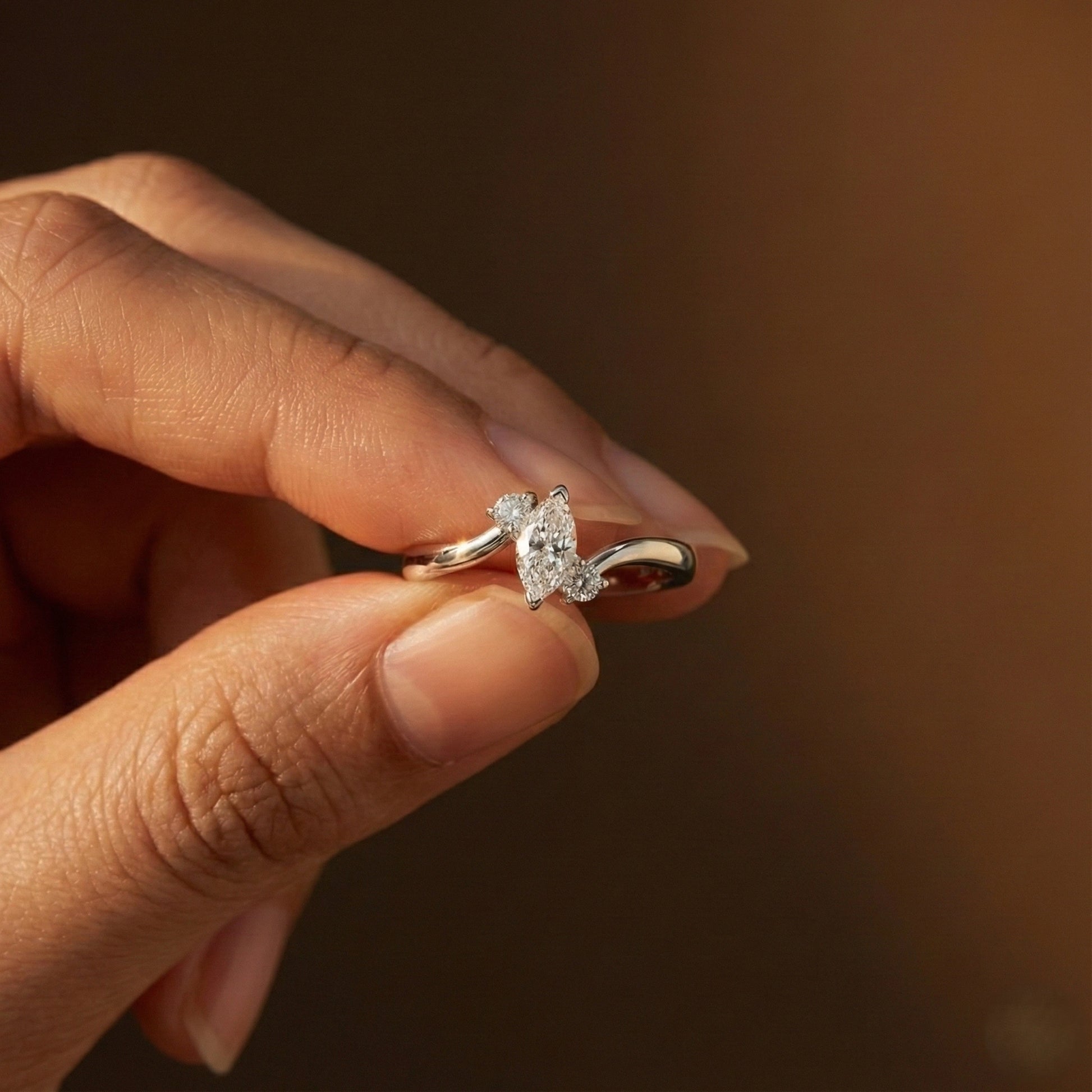 Hand holding a diamond ring with a blurred background