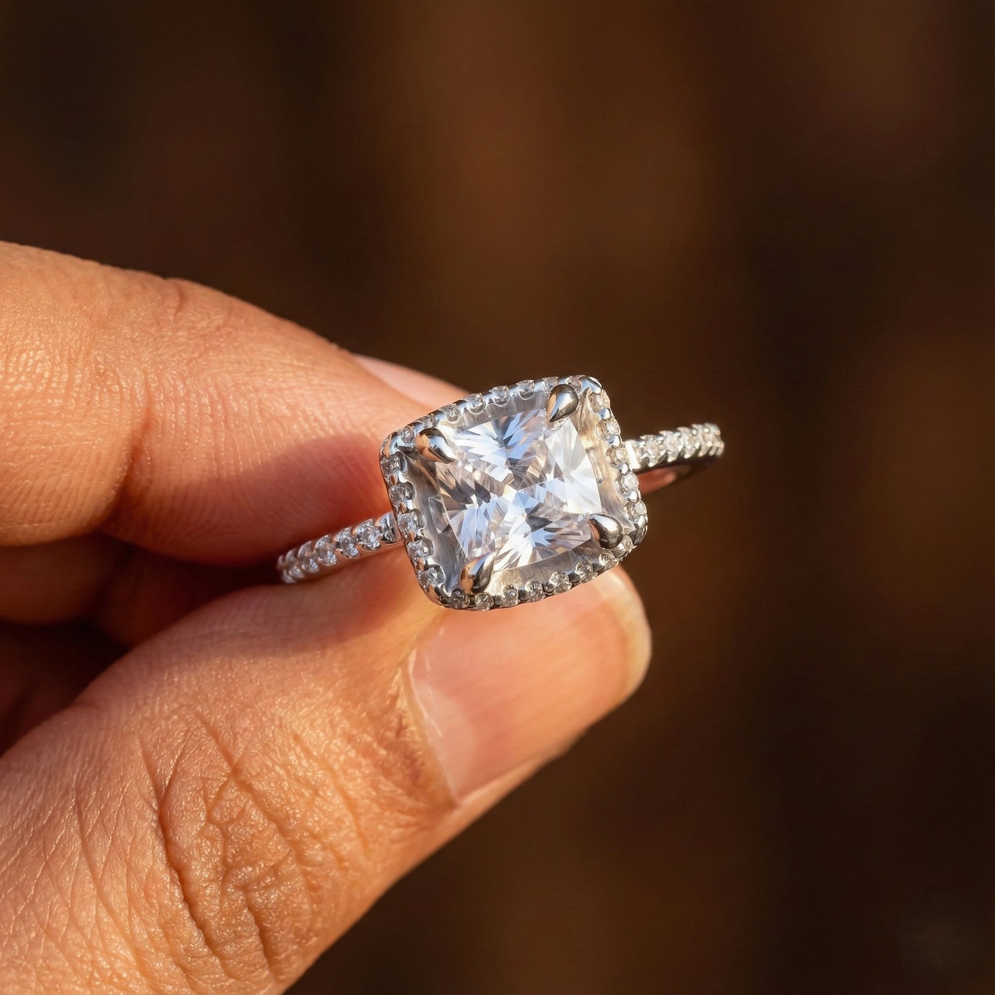Diamond ring held in a hand with a blurred background
