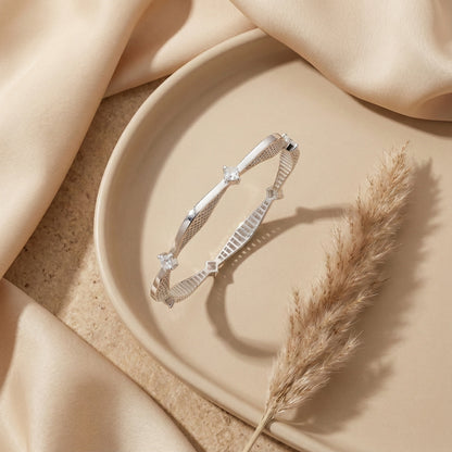 Silver bracelet on a beige plate with a dried plant, on a beige fabric background