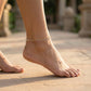 Close-up of a foot wearing an anklet on a sandy surface