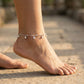 Silver anklet on a foot standing on a stone surface