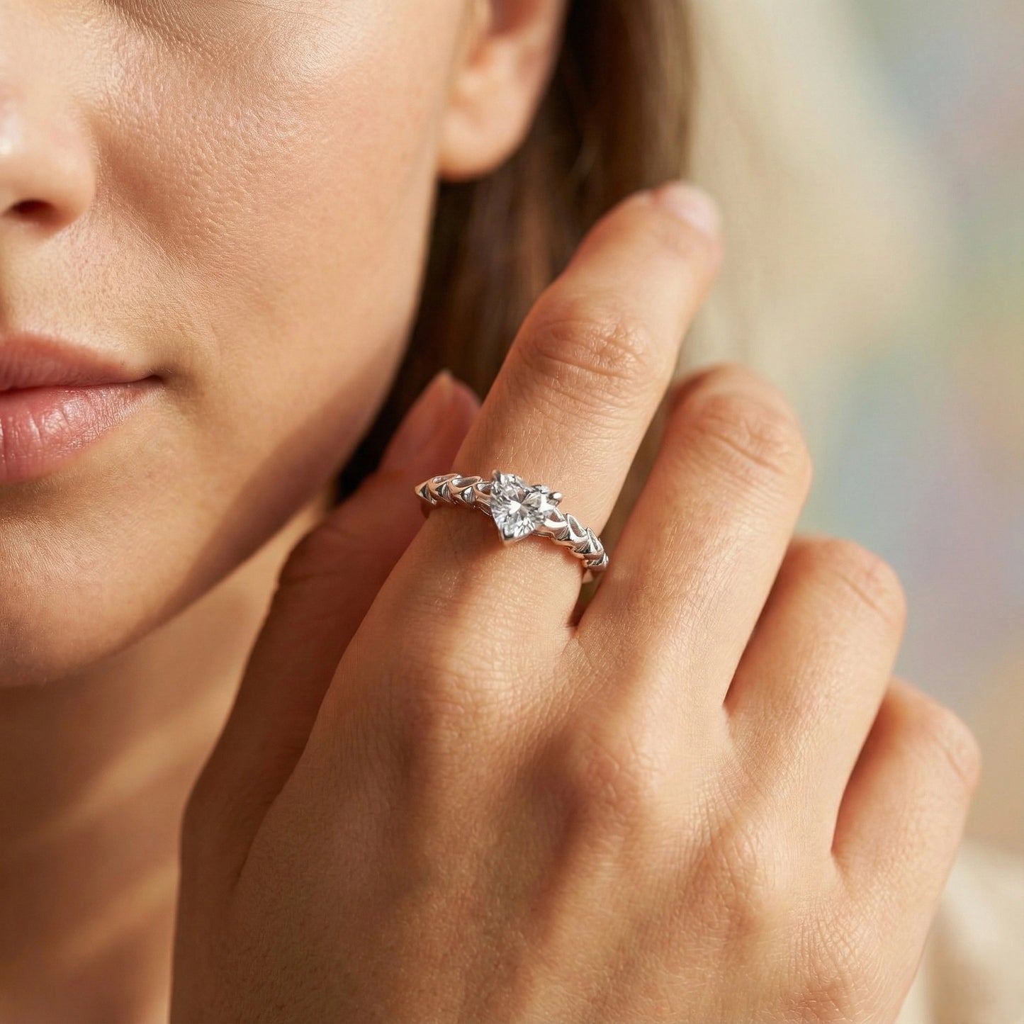 Close-up of a woman's hand wearing a silver ring with a diamond on a blurred background