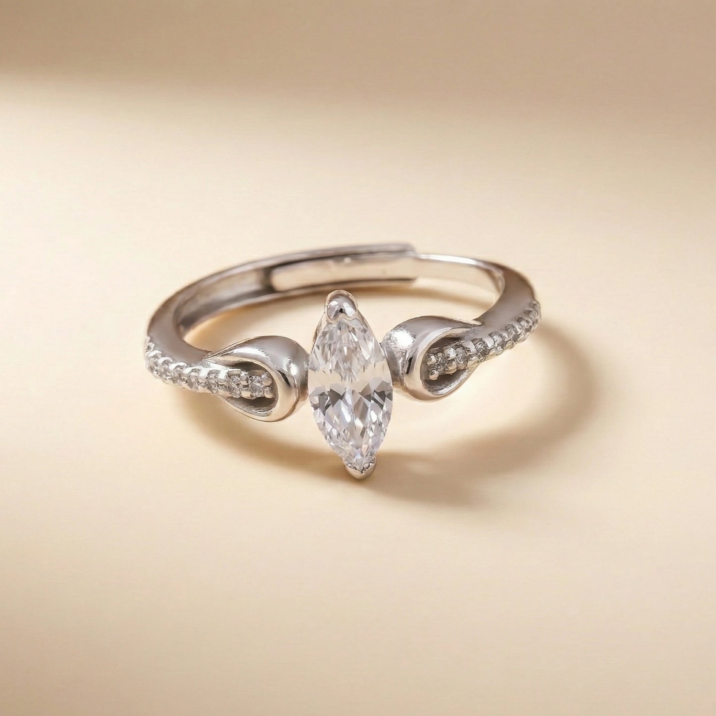 Silver ring with a pear-shaped diamond on a beige background