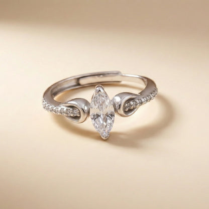Silver ring with a pear-shaped diamond on a beige background