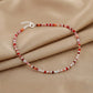 Beaded bracelet with red and white stones on a beige fabric background
