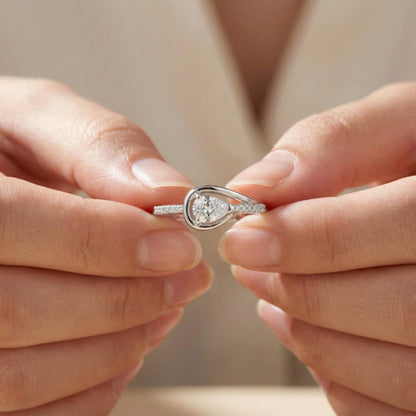 Close-up of hands holding a diamond ring with a heart-shaped center stone.
