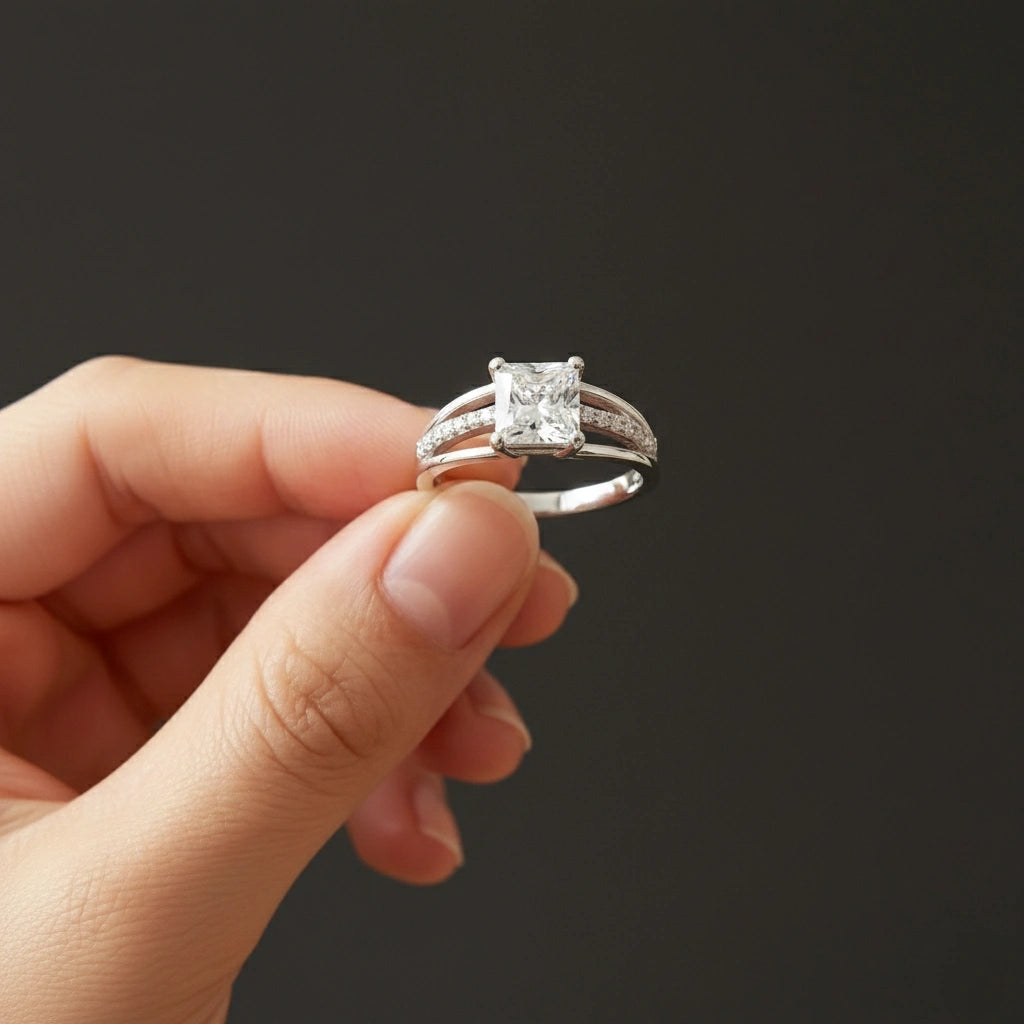 Silver ring with a diamond held in a hand against a dark background
