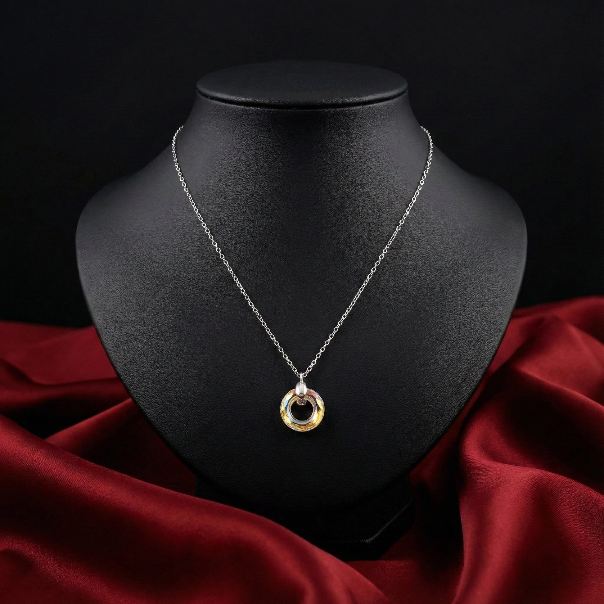 Silver necklace with a gold pendant on a black mannequin bust against a dark background