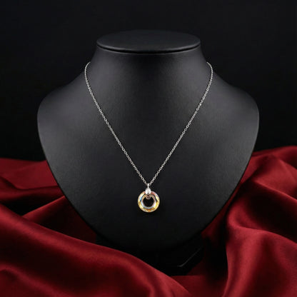 Silver necklace with a gold pendant on a black mannequin bust against a dark background