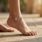 Silver anklet with starfish charms on a foot against a blurred natural background