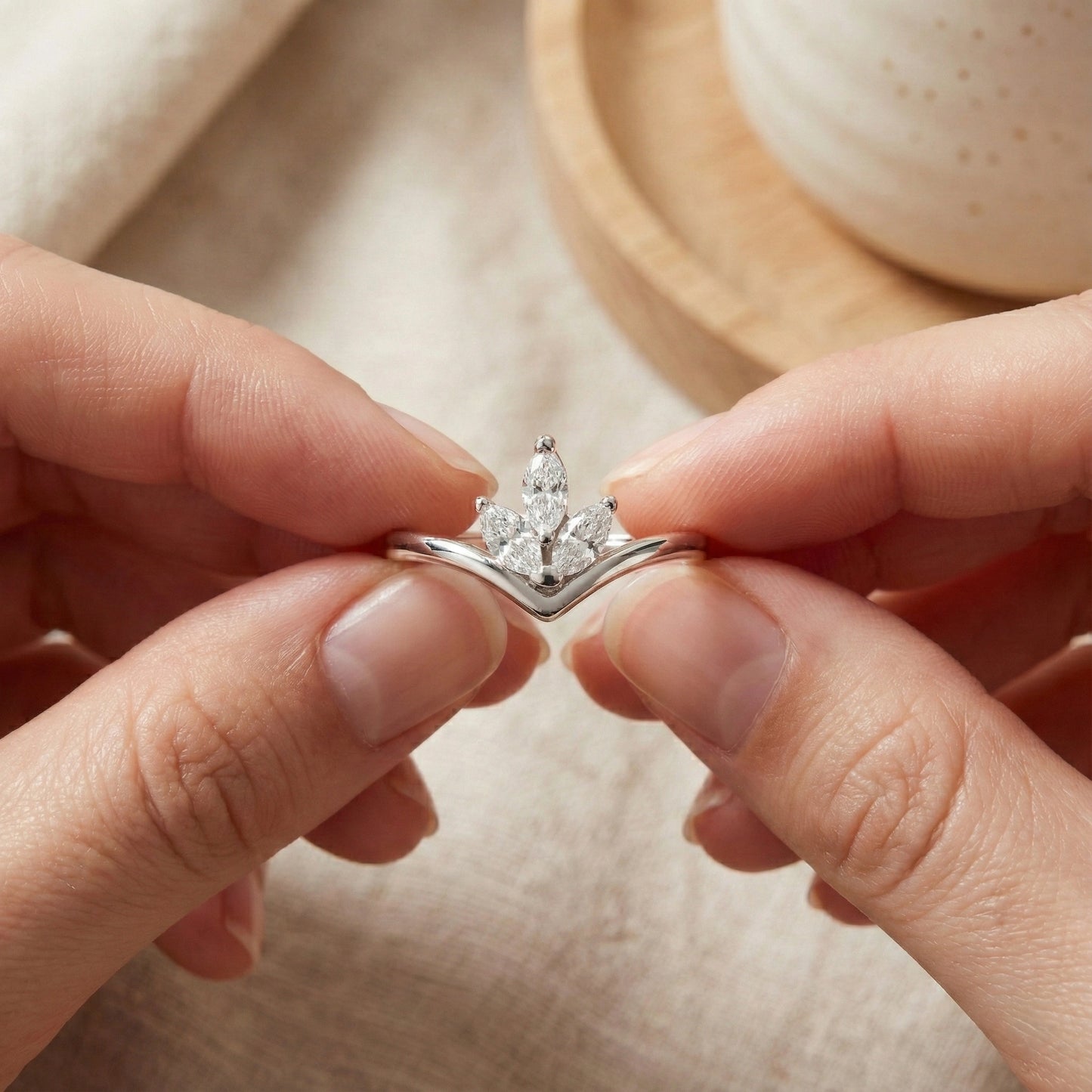 Close-up of hands holding a diamond ring with a neutral background