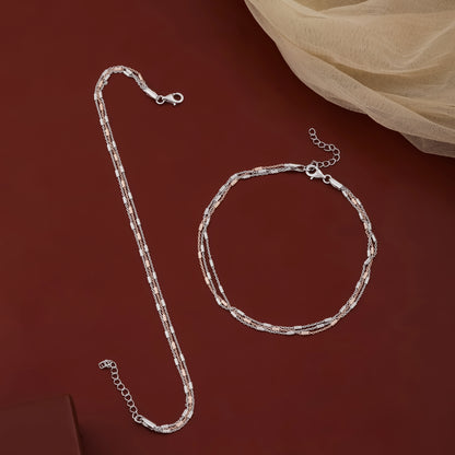 Silver chain necklace and bracelet on a dark red background