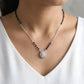 Necklace with a pendant worn by a person in a white top