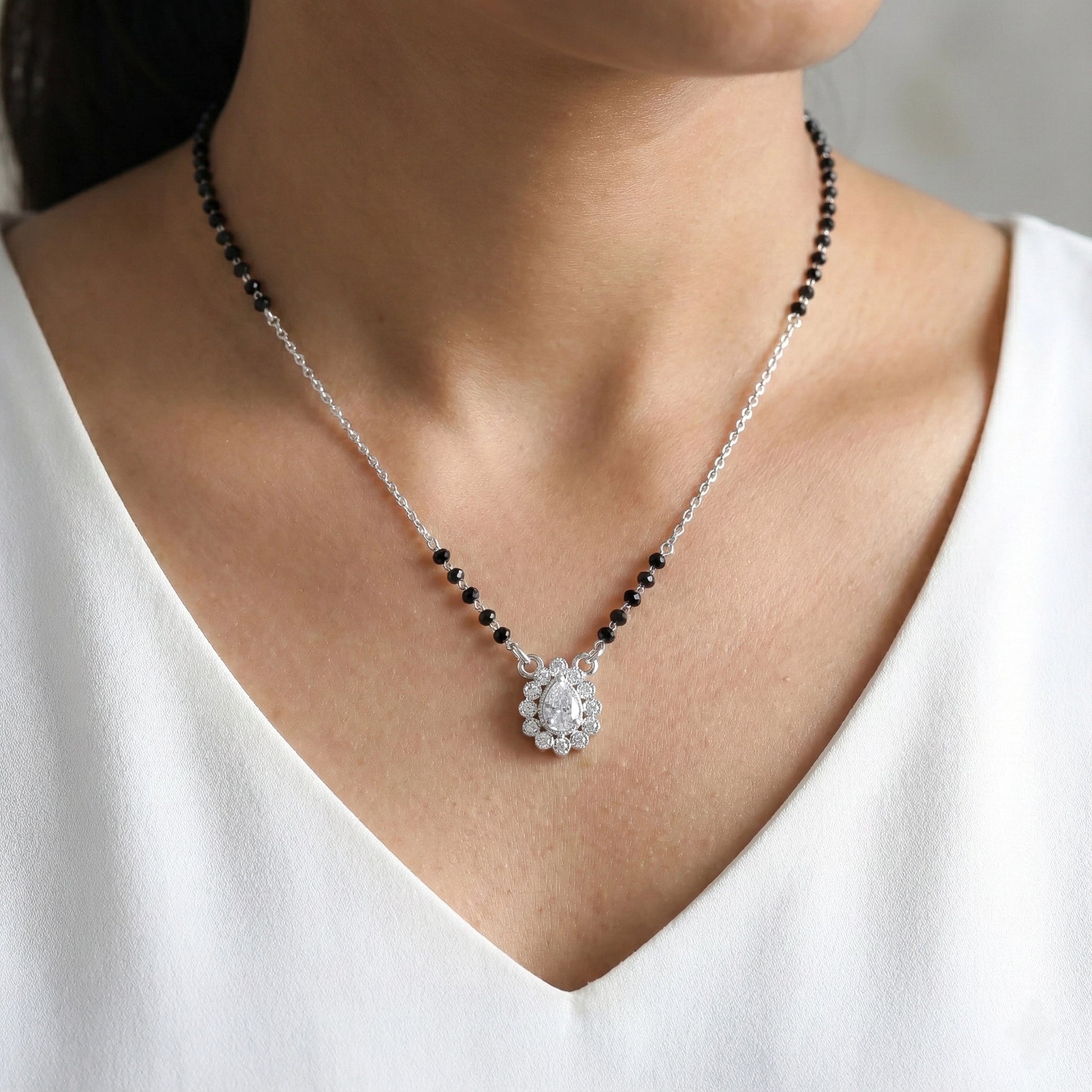 Necklace with a pendant worn by a person in a white top