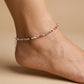 Multicolored beaded anklet on a person's ankle against a beige background