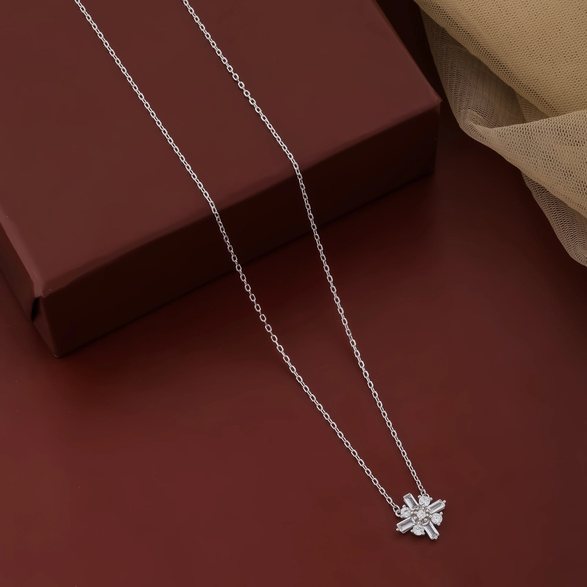Silver necklace with a star-shaped pendant on a brown surface