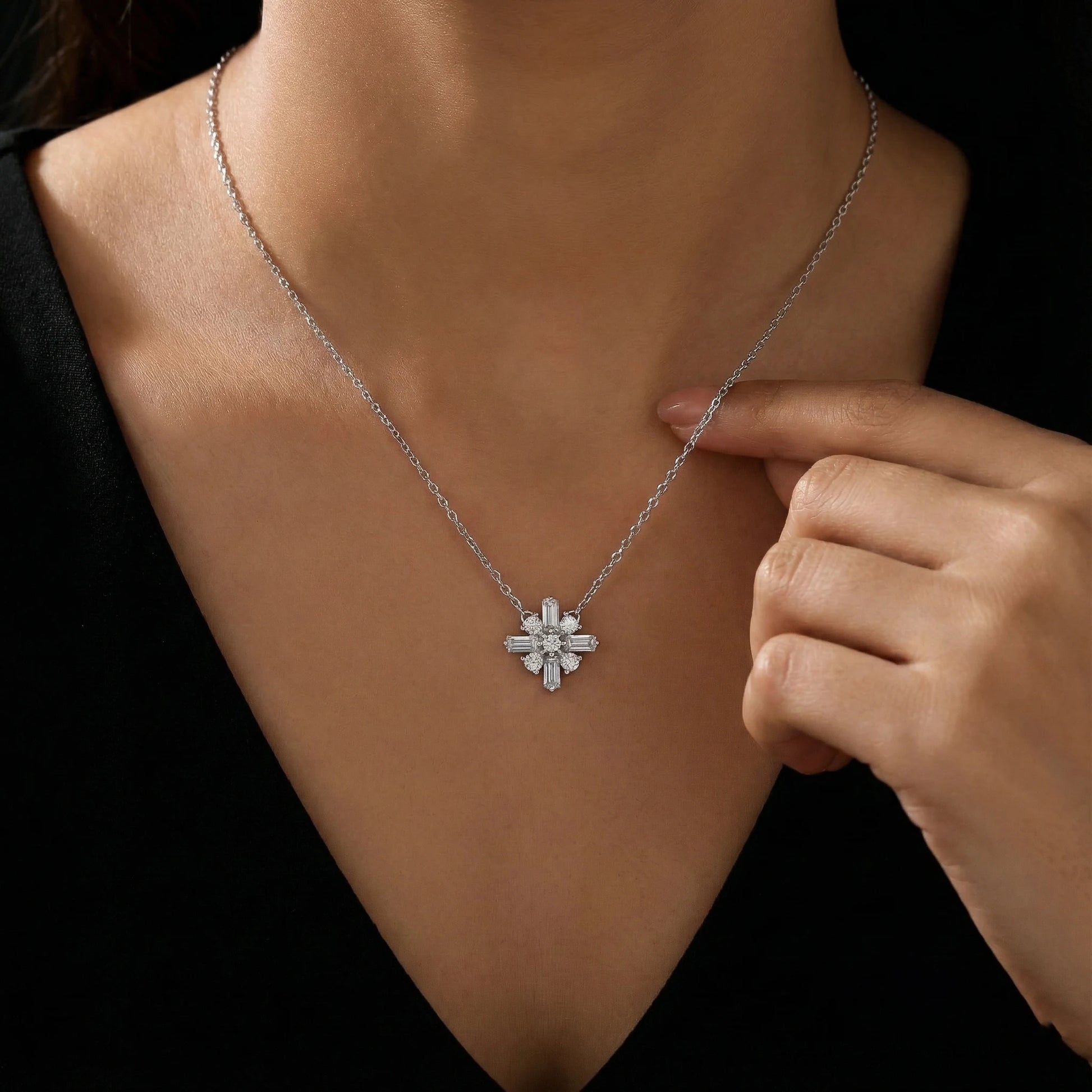 Necklace with a diamond pendant being adjusted on a person against a black background