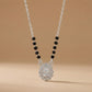 Necklace with black beads and a silver pendant on a beige background