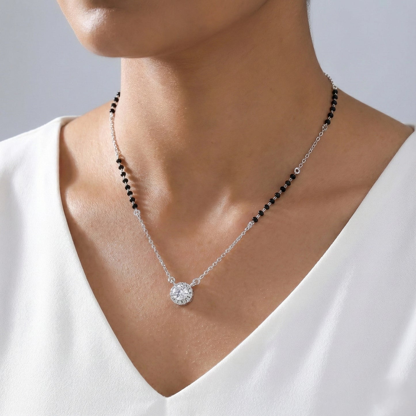 Necklace with a pendant worn by a person in a white top against a neutral background
