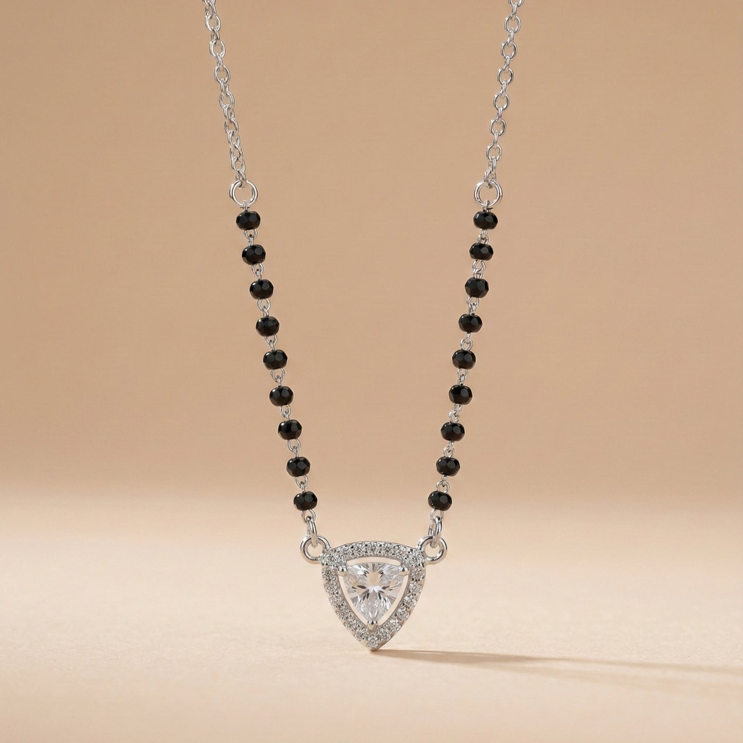 Necklace with a triangular pendant and black beads on a beige background