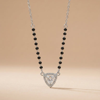 Necklace with a triangular pendant and black beads on a beige background