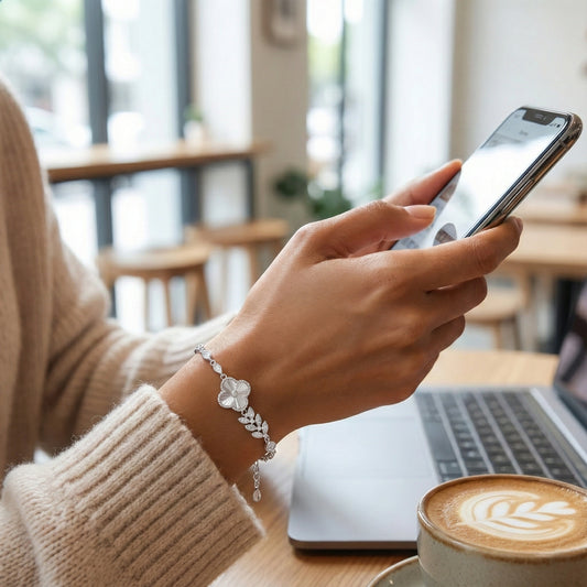 Person using a smartphone with a laptop and coffee in a cafe setting