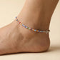 Multicolored beaded anklet on a foot against a beige background