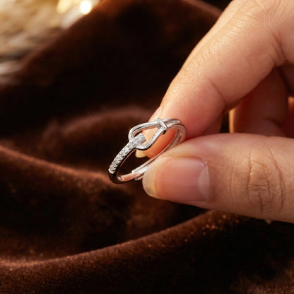 Silver ring with diamonds on a finger against a brown fabric background