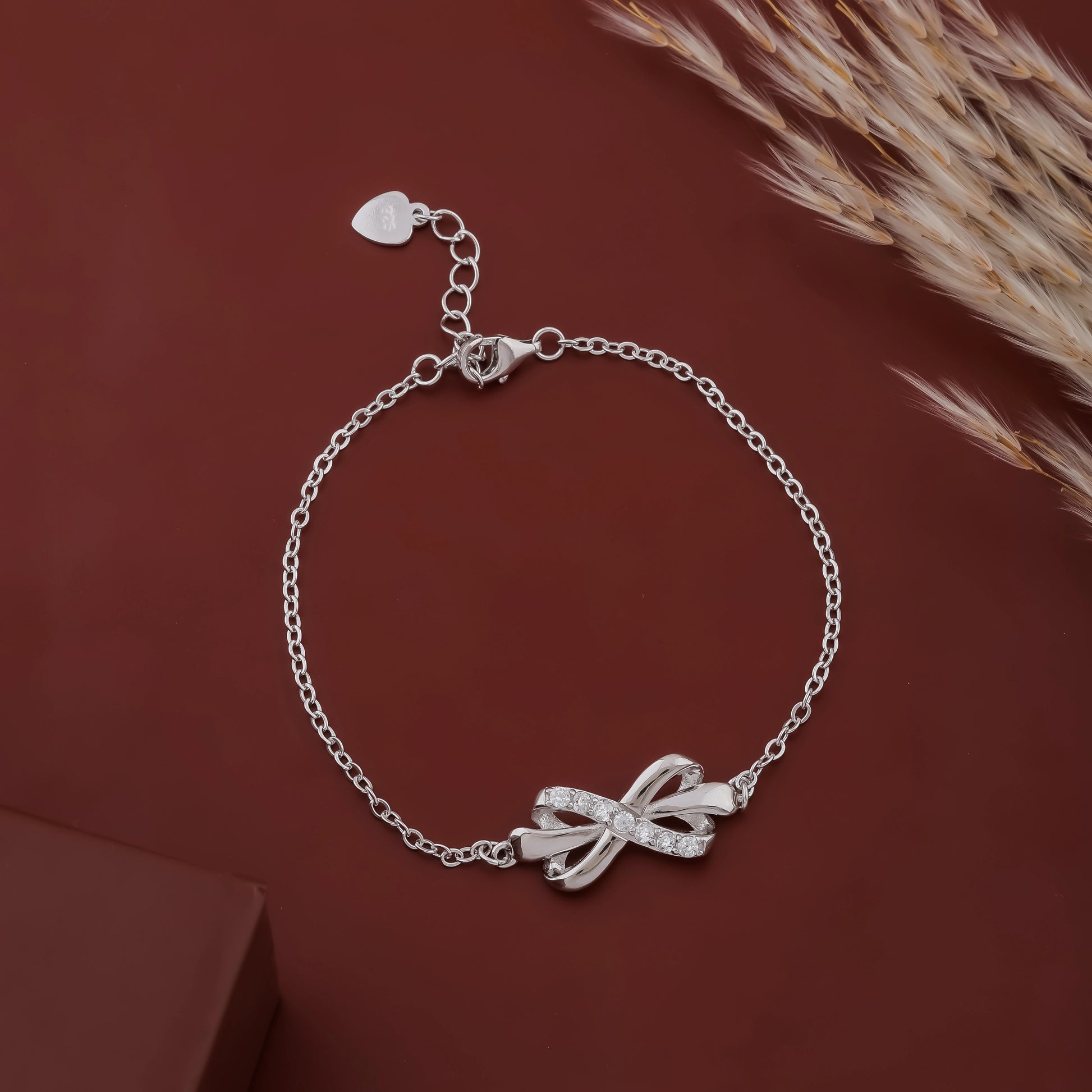 Silver bracelet with a bow charm on a brown background