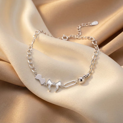 Silver bracelet with heart and chain design on a beige fabric background