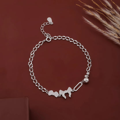 Silver chain bracelet with heart and elephant charms on a brown background